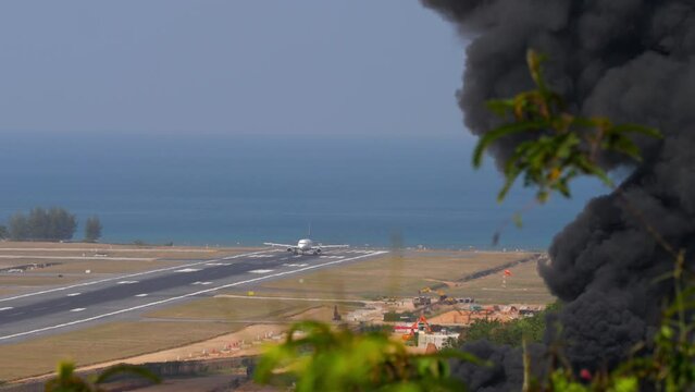 Aircraft landing at Phuket Airport. Airport fire department training. Smoke from a fire near the airport.