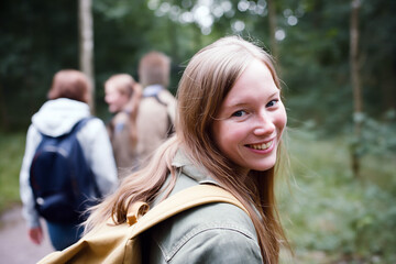 Young woman with backpack glances back at the camera, capturing a moment of anticipation and wanderlust as she embarks on an adventure.

