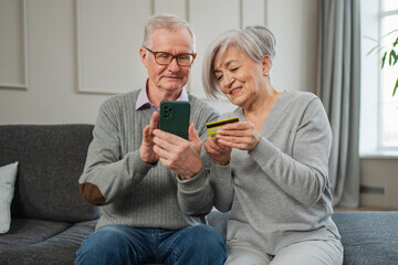Senior couple man woman shopping online with smartphone paying with credit card. Old people buying...