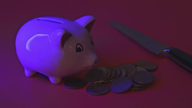 Piggy bank with flashing ambulance an police car lights and hand adding knife in scene