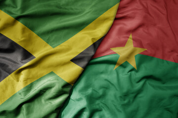 big waving national colorful flag of burkina faso and national flag of jamaica .