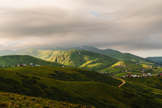 The highland Georgian village of Gomismta at dawn. Georgia travel destination. Mountain landscape of the Caucasus with fresh green meadows and mountain peaks in the background. 
