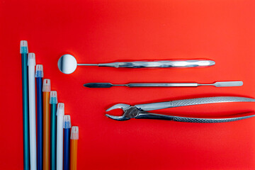 Dental instruments and pencils on red background