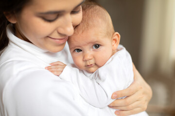 Tenderness and motherhood. Closeup portrait of happy lovely young mother with her little infant baby girl, holding daughter and bonding