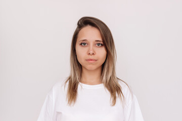Portrait of a young attractive charming caucasian blonde woman in a white t-shirt isolated on a light background