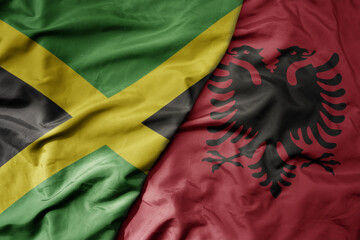 big waving national colorful flag of albania and national flag of jamaica .