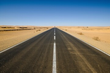 Empty desert road leading towards horizon under clear blue sky in arid landscape - Powered by Adobe