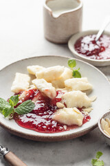 Lazy dumplings, vareniki with raspberry jam decorated with almond petals and mint leaves close up....
