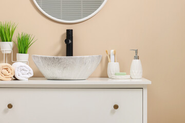 Different bath accessories and personal care products near sink on bathroom vanity