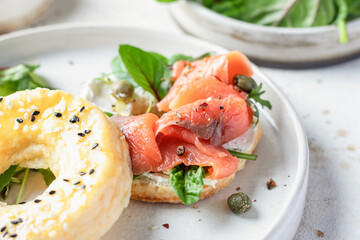 Homemade bagel sandwich with smoked salmon, cream cheese, capers and spinach close up for healthy breakfast
