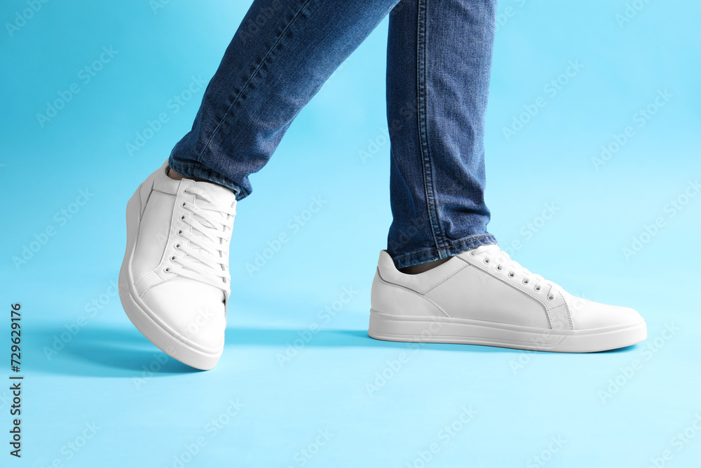 Canvas Prints man wearing stylish white sneakers on light blue background, closeup