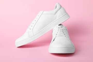 Pair of stylish white sneakers on pink background