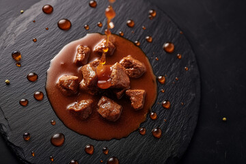 Verlockende Food-Fotografie: Gulaschsuppe auf eleganter schwarzer Steinplatte mit verführerischen Saucen-Spritzern