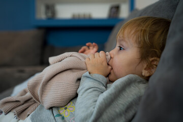 Little baby girl laying on a couch with her blanket, ready to sleep