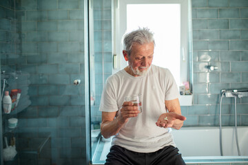Senior man taking pills in home bathroom