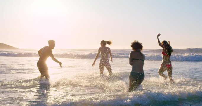 Beach, energy and friends playing in sea together for fun on travel, vacation or holiday in summer. Splash, wave and group of young people in ocean or water outdoor on tropical coast for getaway