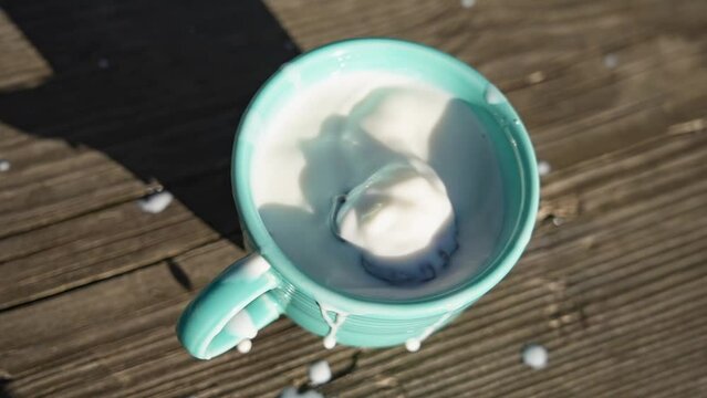 Chocolate covered pretzel falling inside mug with milk in slow motion