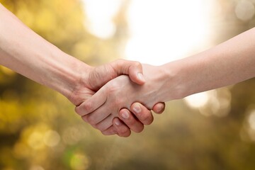 Two people shaking hands on outdoor background