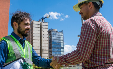 Construction workers shaking hands in construction site  in sunny day