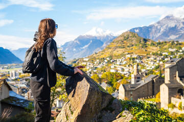 Woman admiring the view of historical Sion town,spectacular set in the swiss Alps mountains valley,...