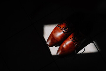 Valmiera, Latvia - July 7, 2023 - A pair of brown leather dress shoes on a tiled floor, highlighted...