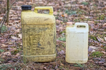 two old dirty yellow plastic canister stand on the gray ground in the street