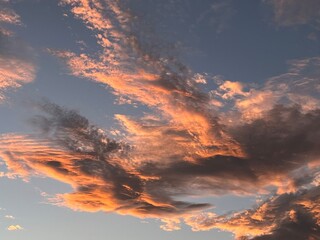 Cloudscape of pink and grey at sunset against a grey/blue sky.
