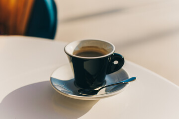 Cup of black coffee on a table in a street cafe.