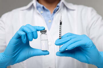 Doctor holding syringe and glass vial, closeup view