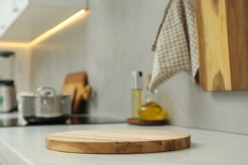Wooden cutting board on white countertop in kitchen. Space for text