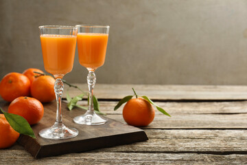 Delicious tangerine liqueur and fresh fruits on wooden table, space for text