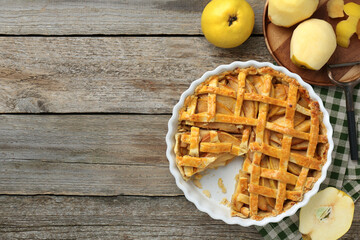 Tasty homemade quince pie, fresh fruits and peeler on wooden table, flat lay. Space for text