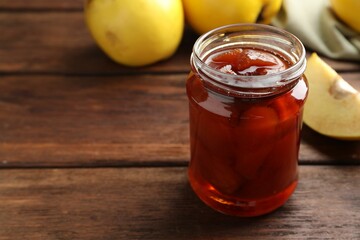 Tasty homemade quince jam in jar on wooden table, closeup. Space for text