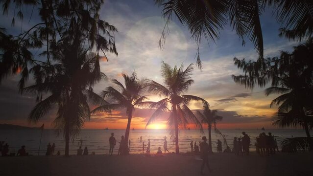Silhouetted people and palms near sea. Sunset at tropical White beach, Boracay island, Philippines, slow motion 4k