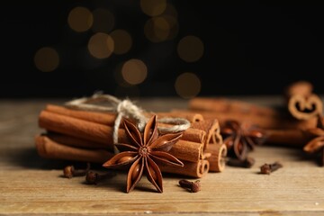 Bunch of cinnamon sticks, anise star and dry clove buds on wooden table, closeup - obrazy, fototapety, plakaty