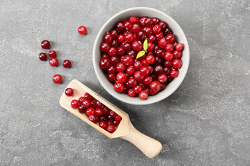 Fresh ripe cranberries in bowl and scoop on grey table, flat lay