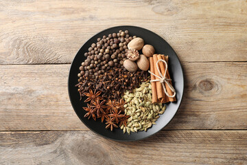 Different spices and nuts on wooden table, top view