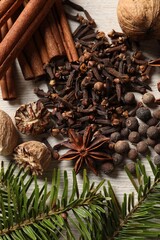 Different spices and fir branches on wooden table, flat lay