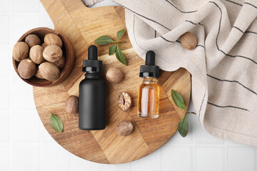 Obraz na płótnie Canvas Nutmeg essential oil and nuts on white table, top view