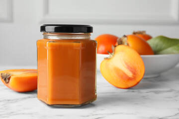 Delicious persimmon jam and fresh fruits on white marble table