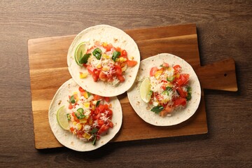 Delicious tacos with vegetables and lime on wooden table, top view