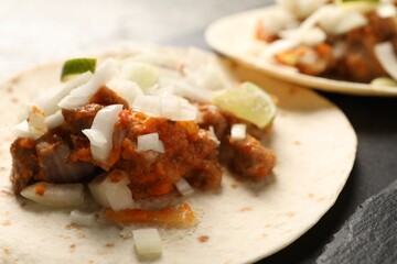 Delicious tacos with vegetables, meat and lime on dark table, closeup