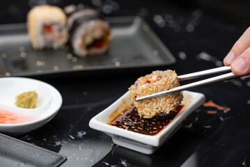 Close up of hands with chopsticks eating japanese food. Traditional asian rolls. Maki sushi with vegetables and tuna
