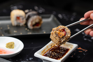 Close up of hands with chopsticks eating japanese food. Traditional asian rolls. Maki sushi with vegetables and tuna