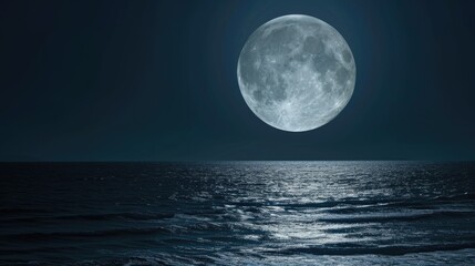 A full moon over the ocean at night.