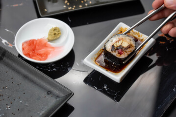 Close up of hands with chopsticks eating japanese food. Traditional asian rolls. Maki sushi with vegetables and tuna