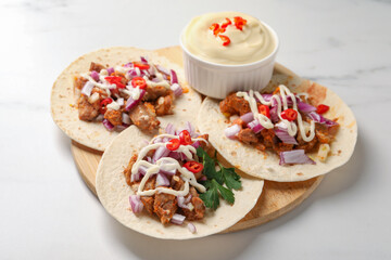 Delicious tacos with vegetables, meat and sauce on white table