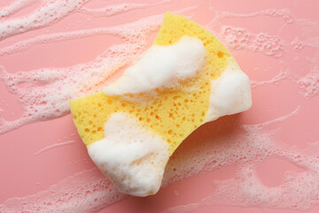 Yellow sponge with foam on pink background, top view