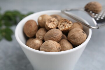Nutmegs in bowl and grater on light table, closeup