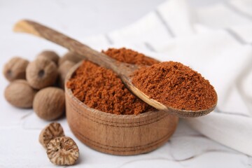 Nutmeg powder and seeds on white table, closeup